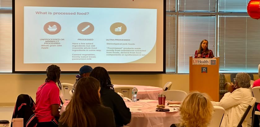 The audience of breast cancer survivors faces a projector screen and podium where Dr. Julie Bradley presents information about “Food as Medicine” 